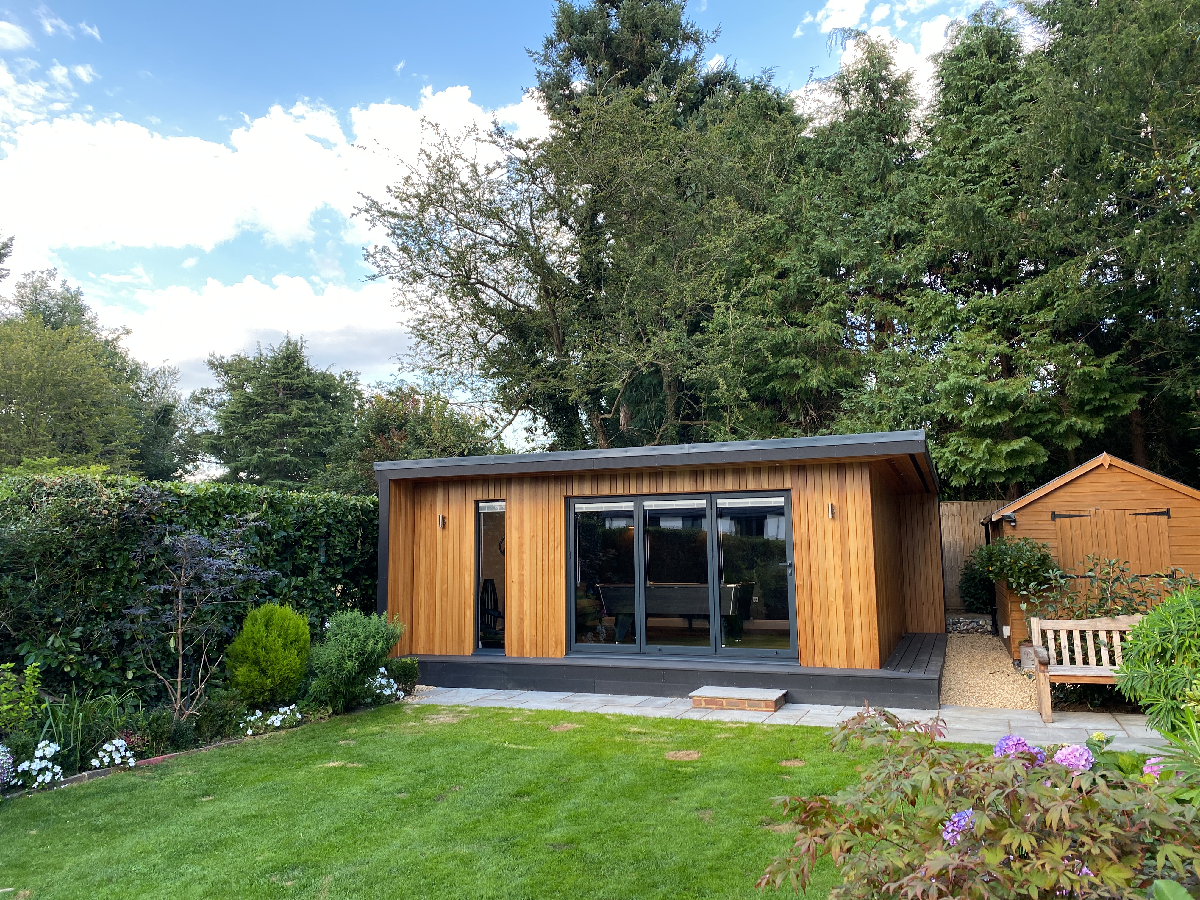 garden studio in horsham with bifold doors and red cedar finish wraparound decking and canopy overhang